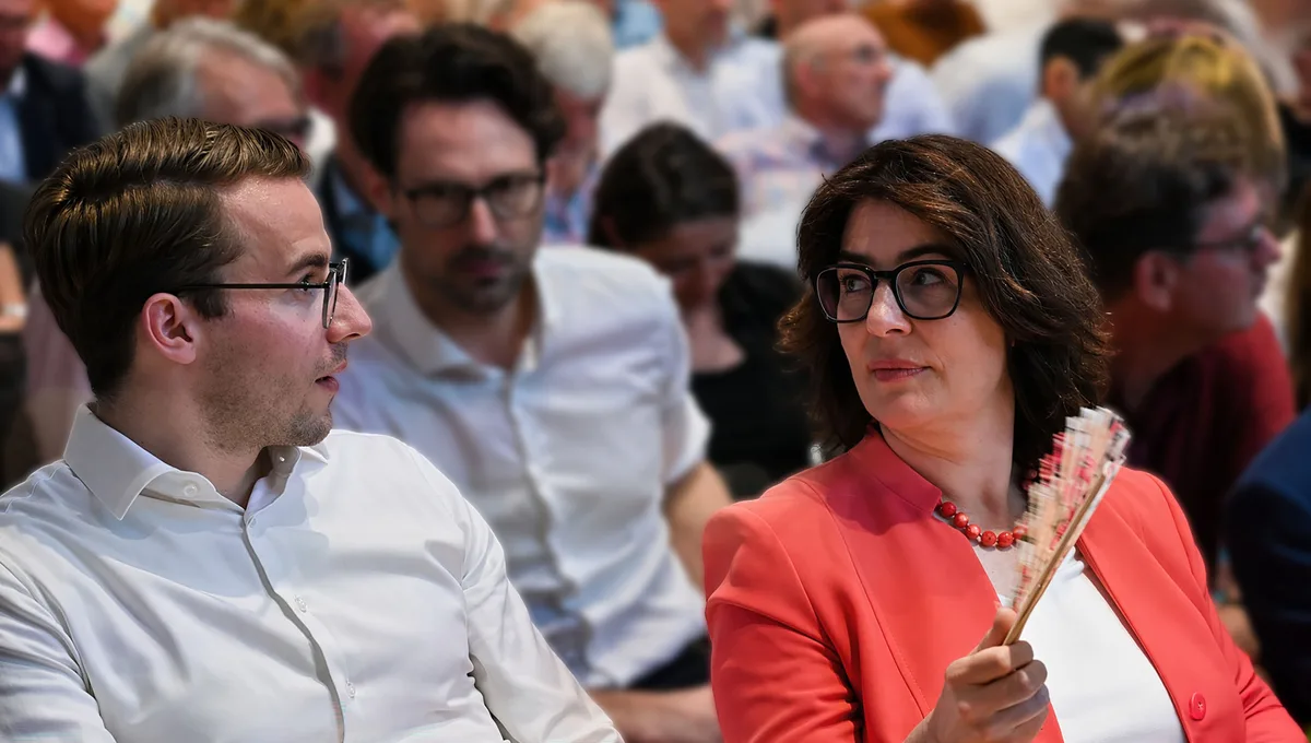 Monika Keller im Gespräch mit Parteikollege Andri Silberschmidt. Monika Keller wedelt sich mit einem Fächer Luft zu und ist ins Gespräch mit Andri Silberschmidt vertieft.